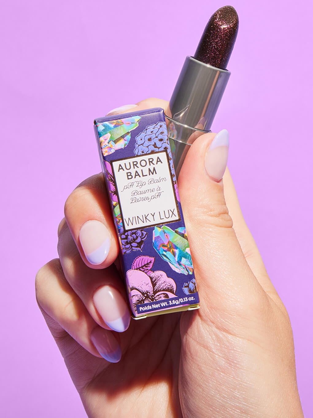 model hand holding up aurora ph lip balm with box on purple background model hand holding up aurora ph lip balm with box on purple background