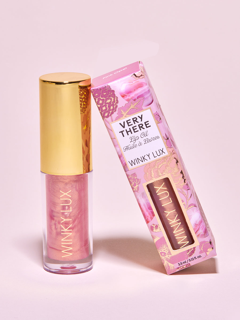 Pink opal shimmer -- two lip oils leaning against each other, one in box. 