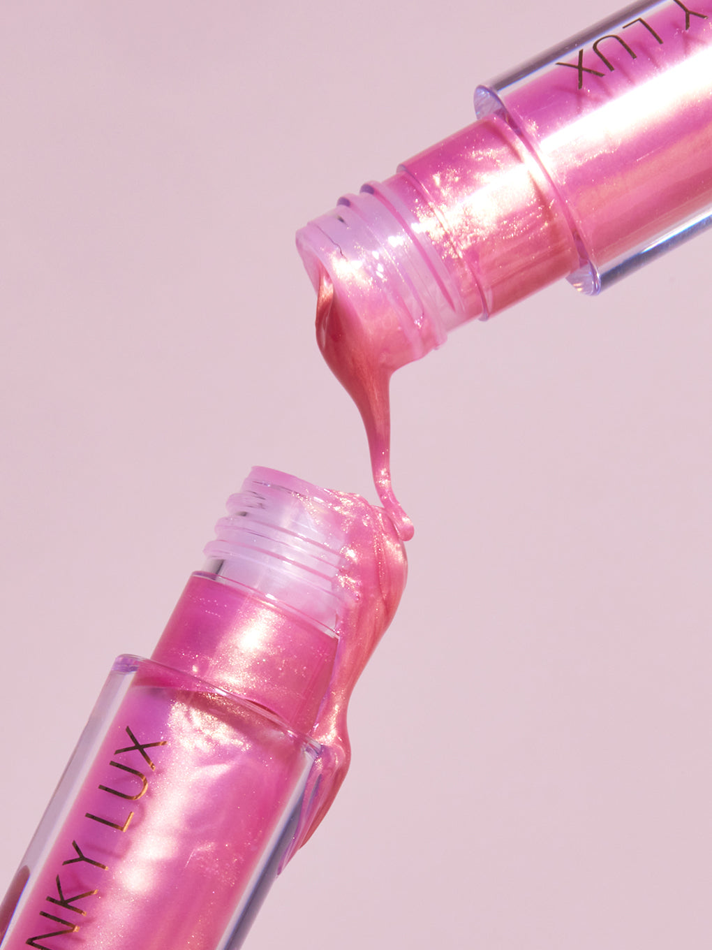 Pink opal shimmer -- two golden pink lip oils pouring product out stylized shot