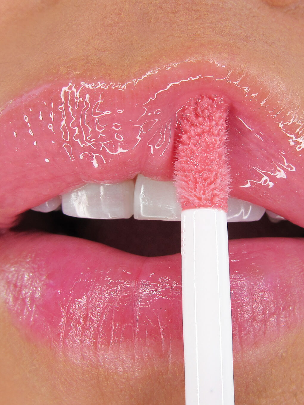 close up of light pink lip oil being applied to upper lip