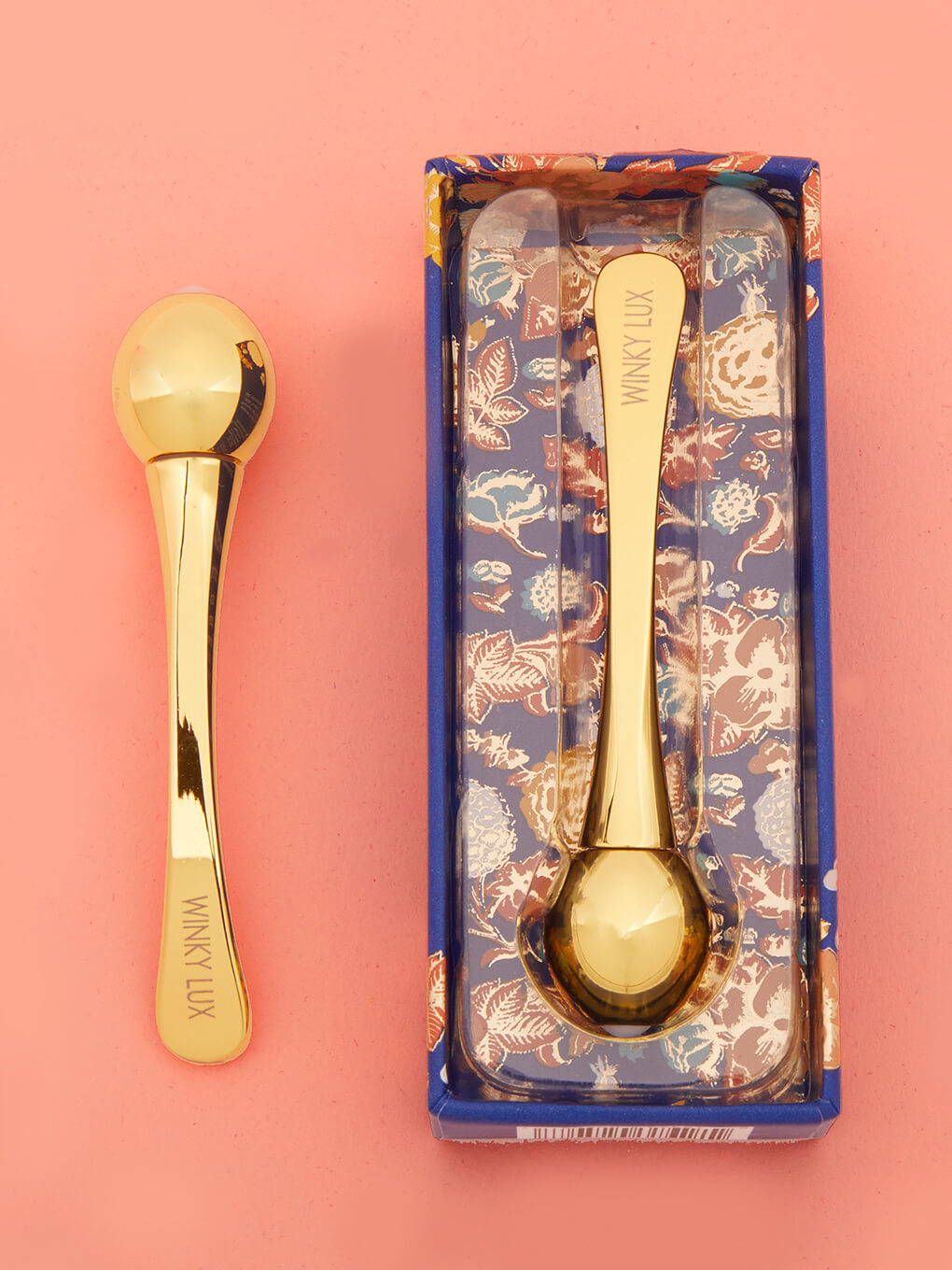 eye cream applicator lying down next to box on orange background