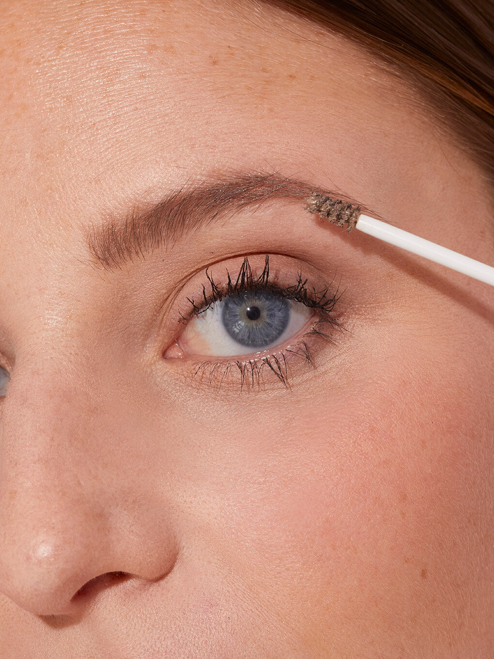 blonde -- close up of blonde model applying unibrow tinted brow gel