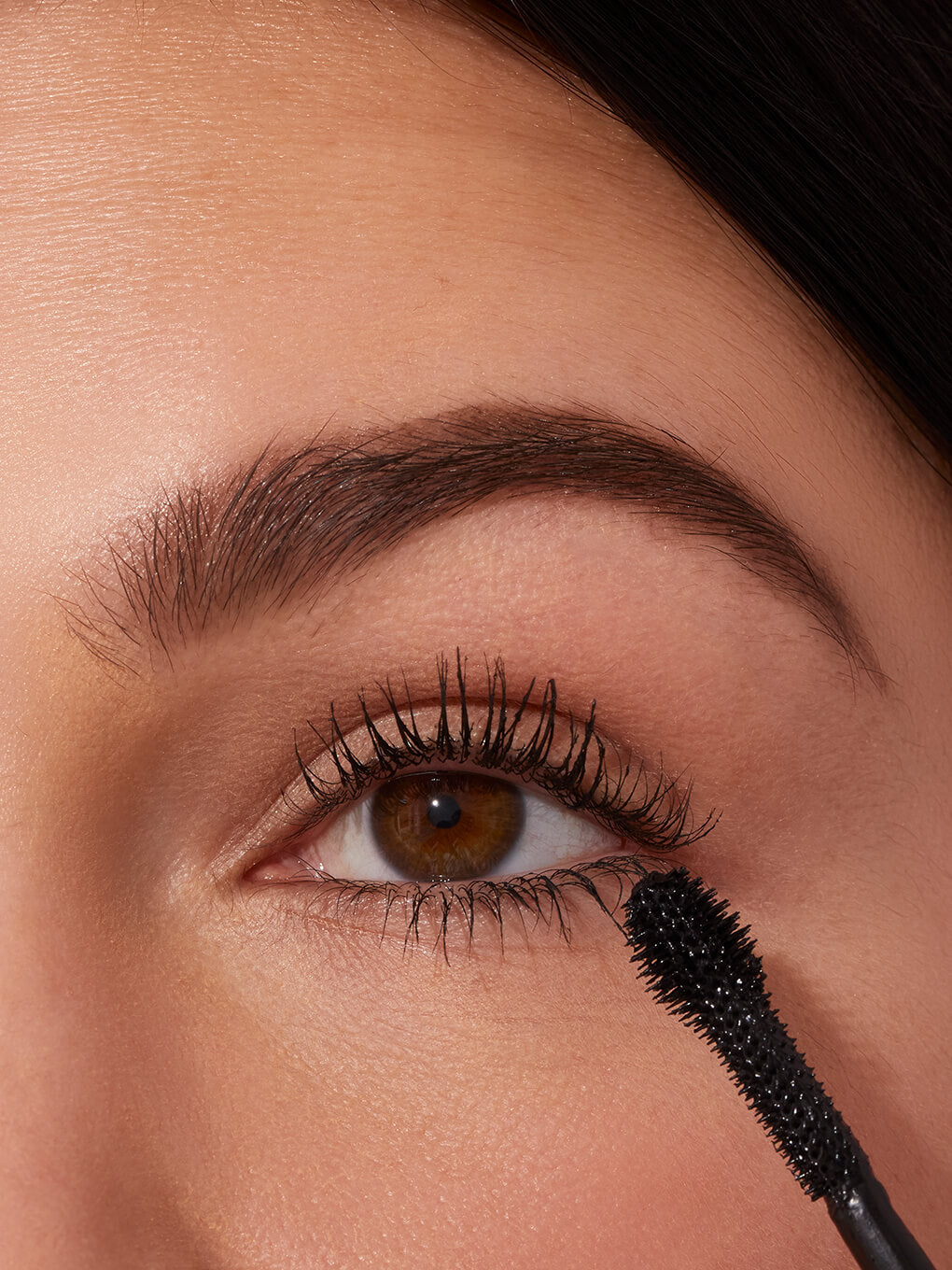 close up of brunette model applying extravalash mascara to lashes