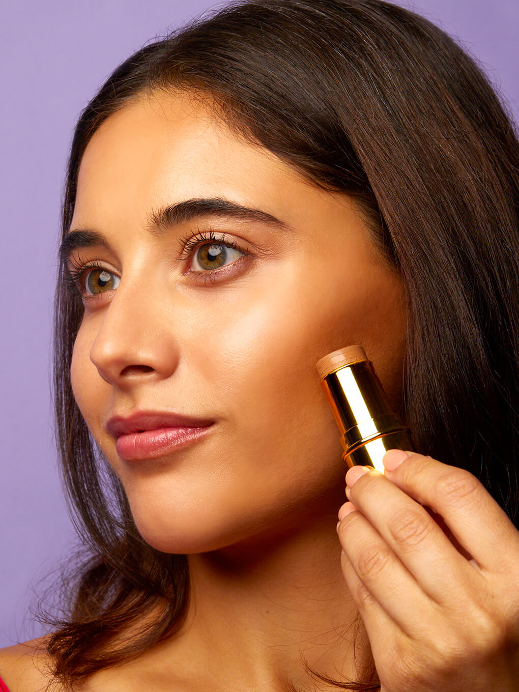 Golden Touch -- model applying bronze age cream bronzing stick to cheek bone