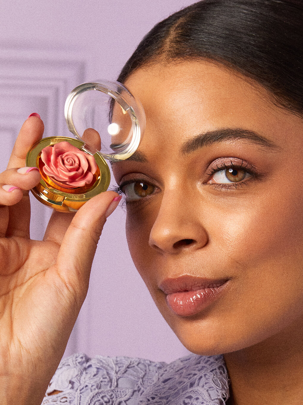 Rosé -- model holding up cheeky rose cream highlighter next to face