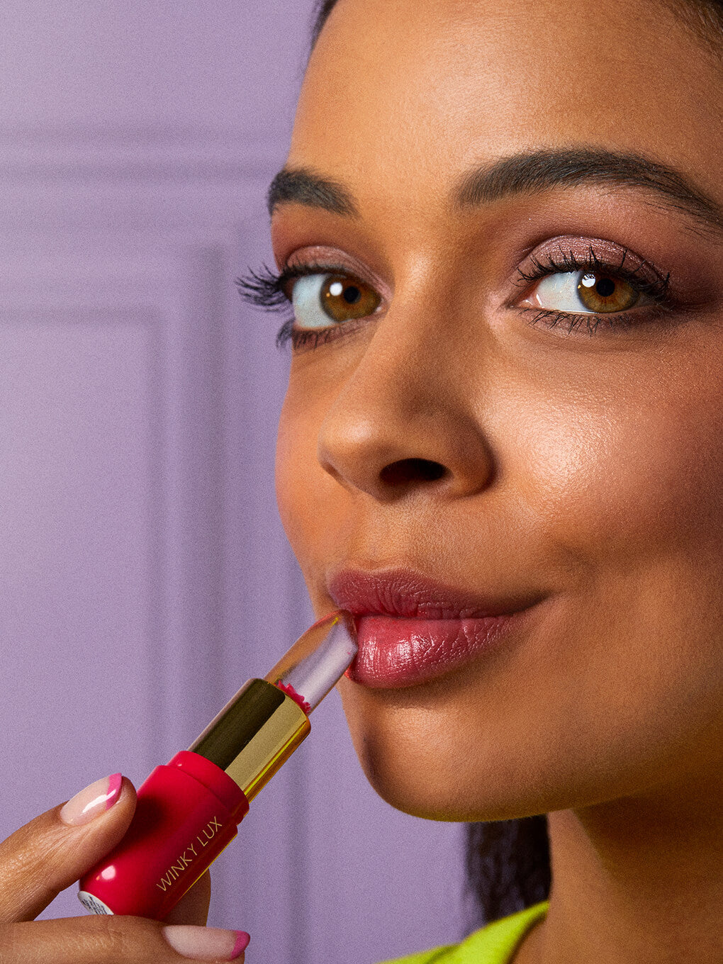 blue -- brunette model applying flower ph lip balm on purple background