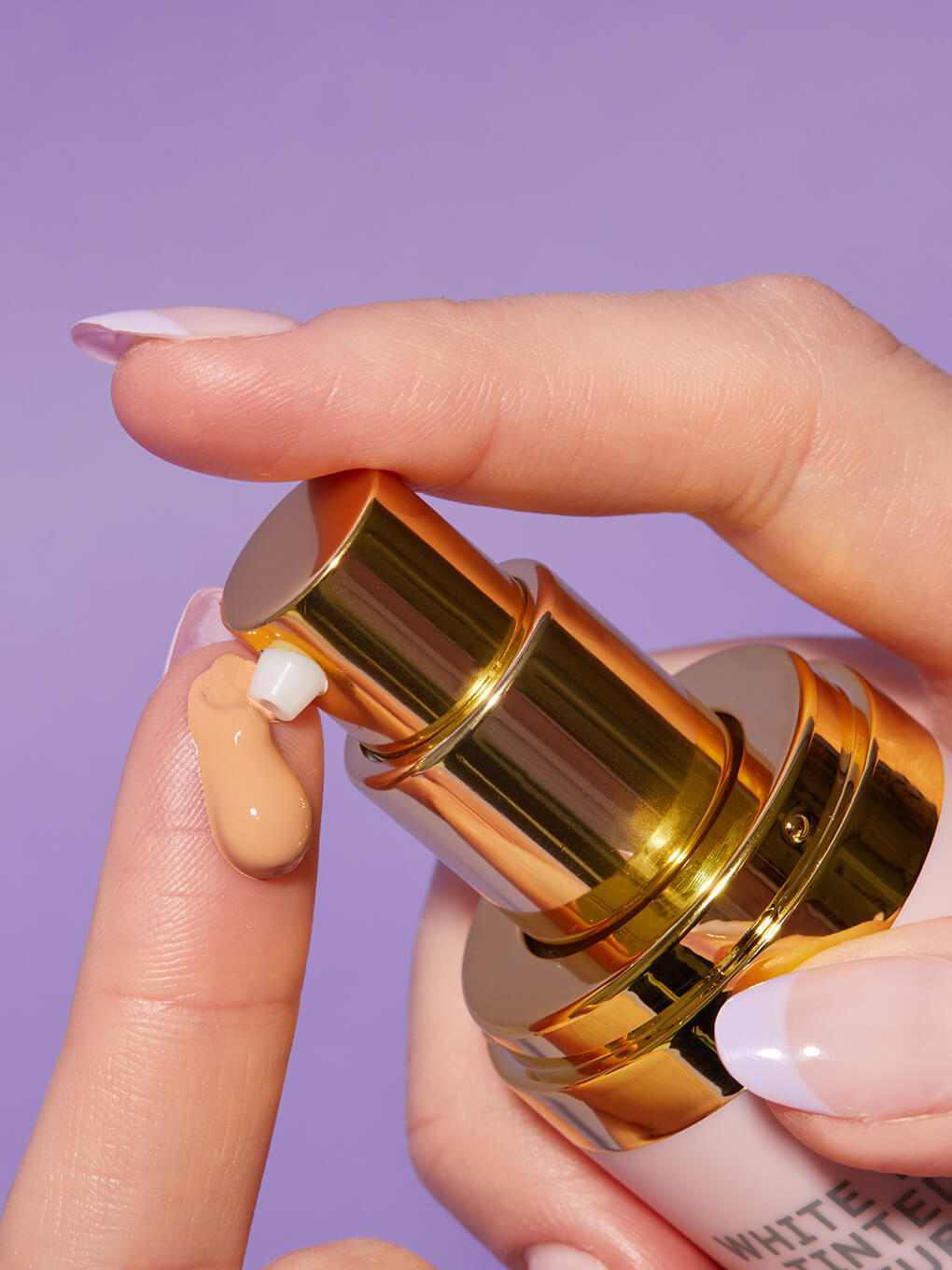 Rich -- close up of hand applying drop of tinted moisturizer spf 30 on finger