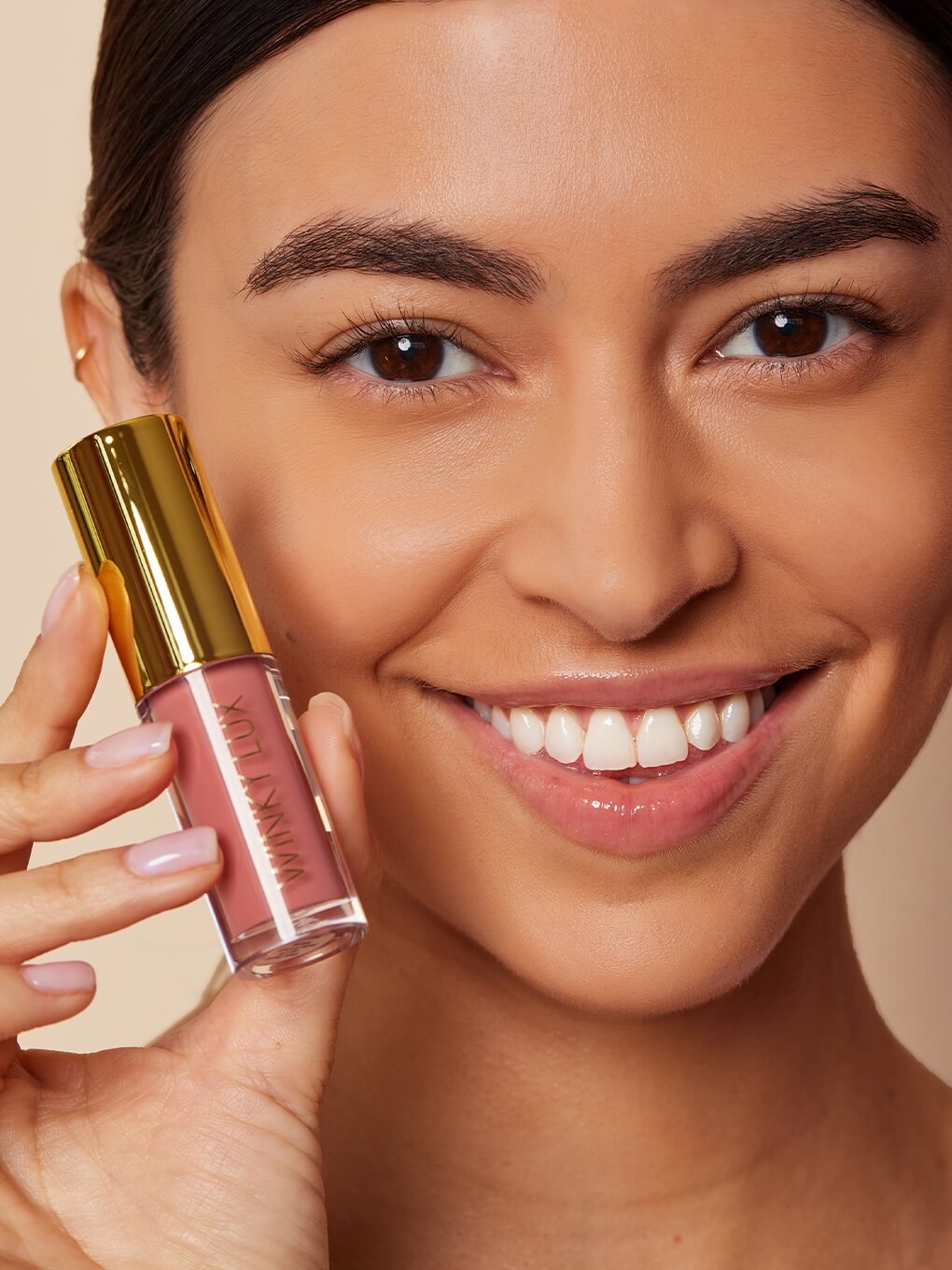 model smiling holding up very there lip oil next to cheek