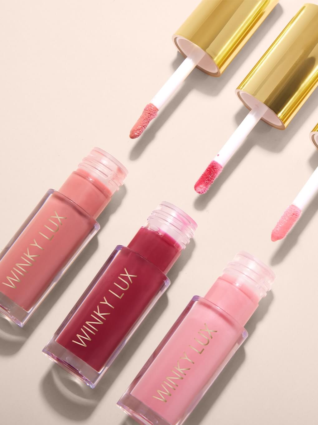 three very there lip oils flat lay with applicators coming out of component