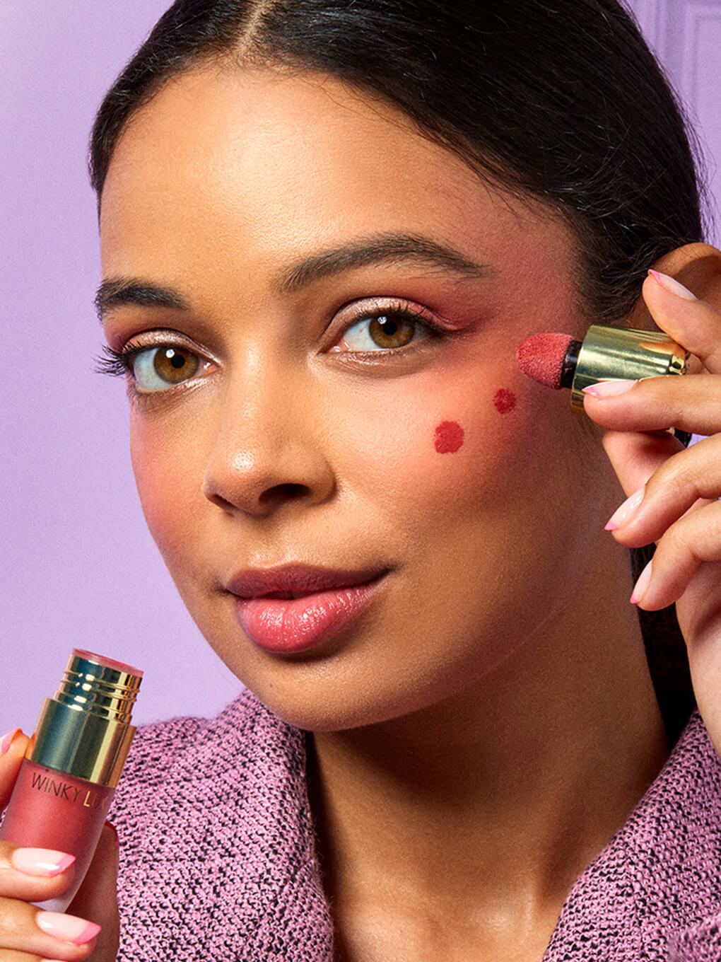 Queen -- model applying cheeky rose liquid blush on cheeks