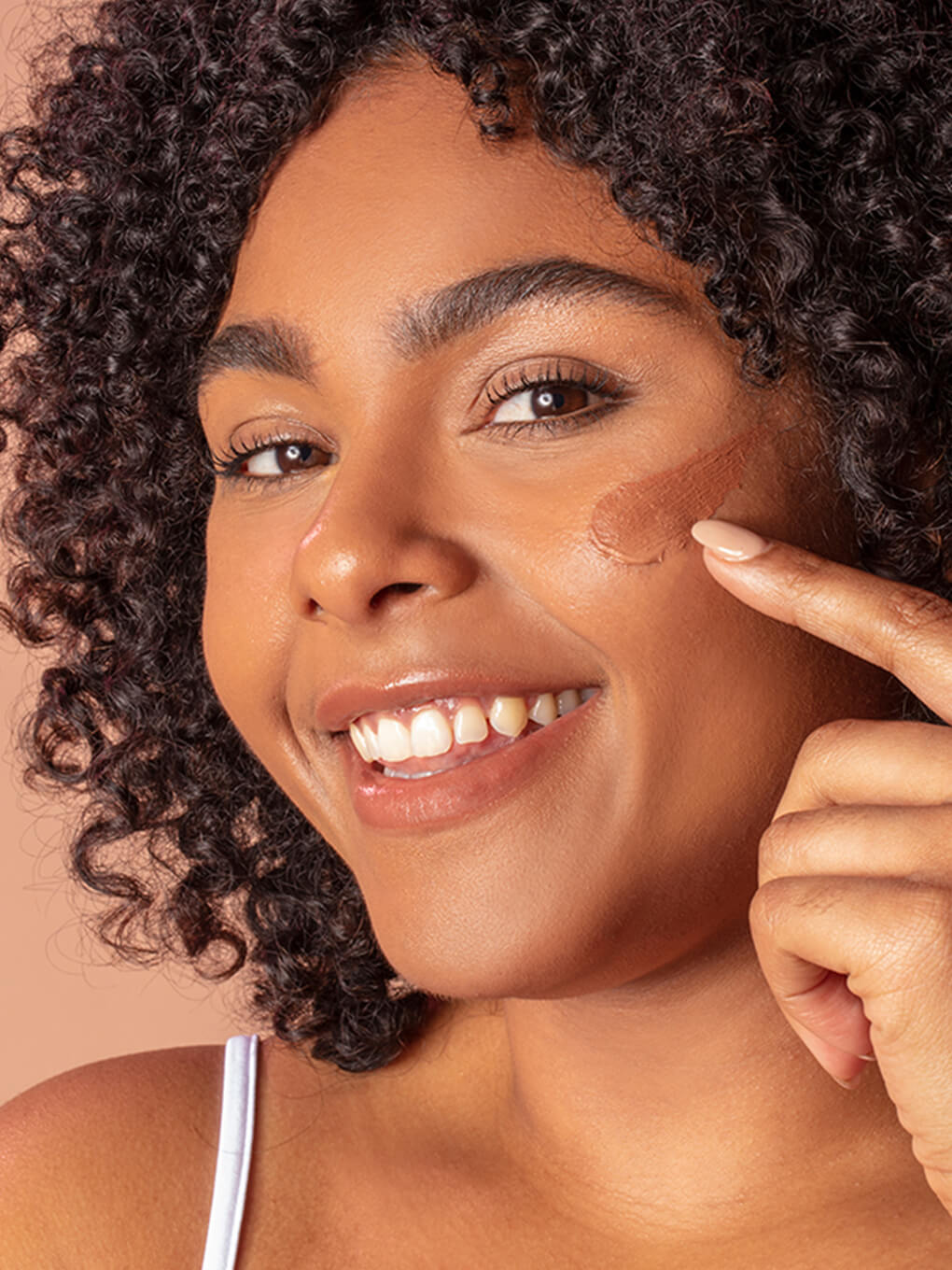 Deep -- close up of brunette model smiling with tinted moisturizer spf 30 on her cheek bone