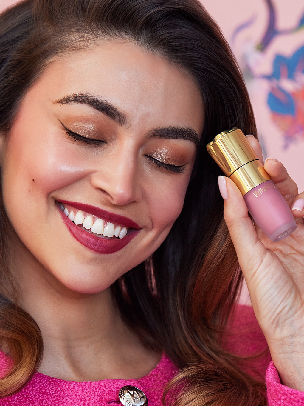 brunette model smiling holding cheeky rose liquid blush up to face