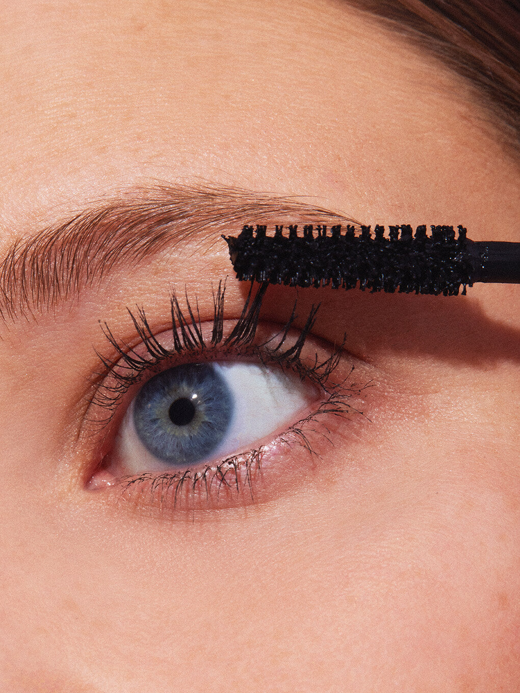 close up of model applying so extra volumizing mascara to eyelashes