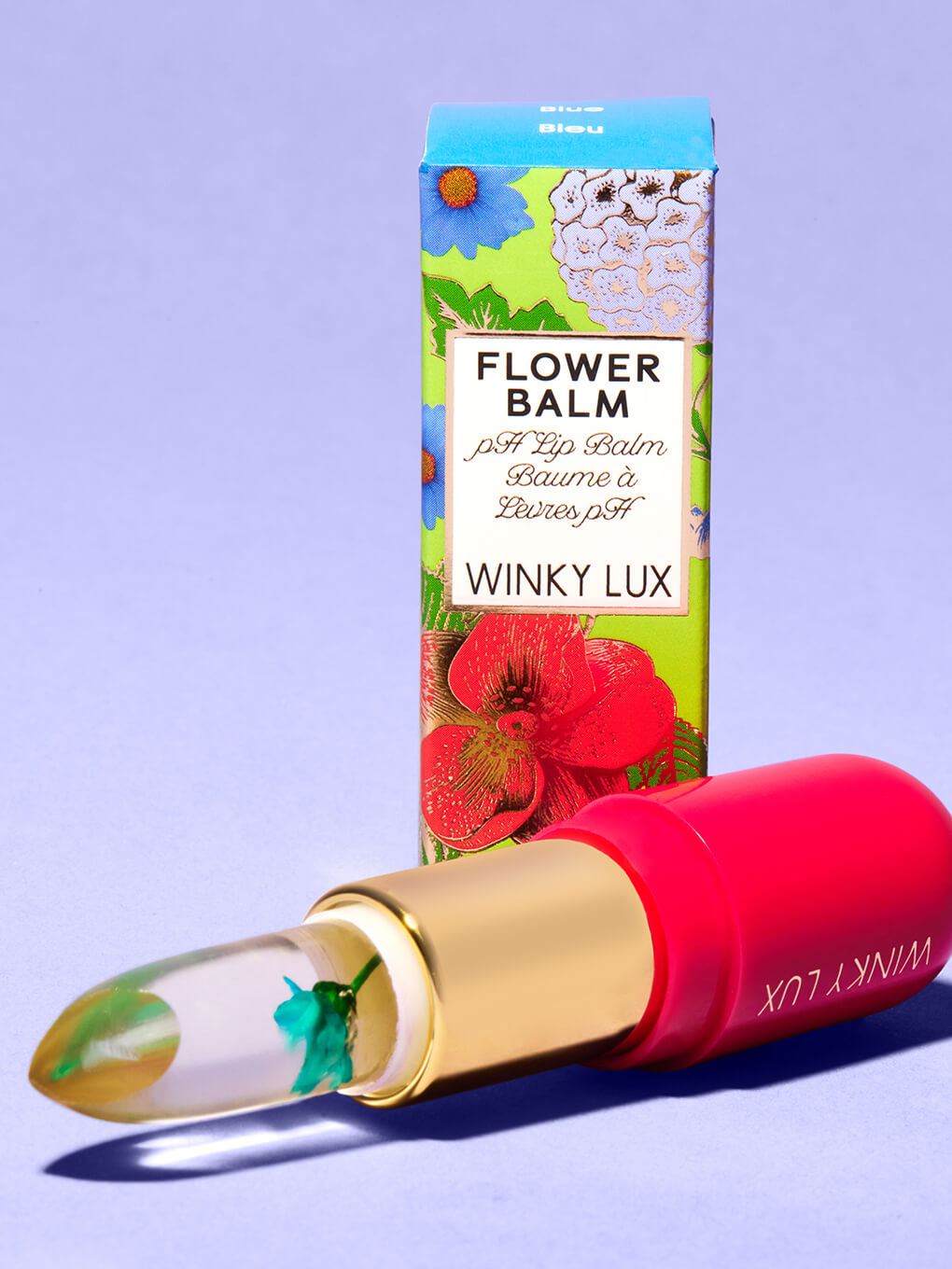 blue -- flower ph lip balm laying next to box on purple background