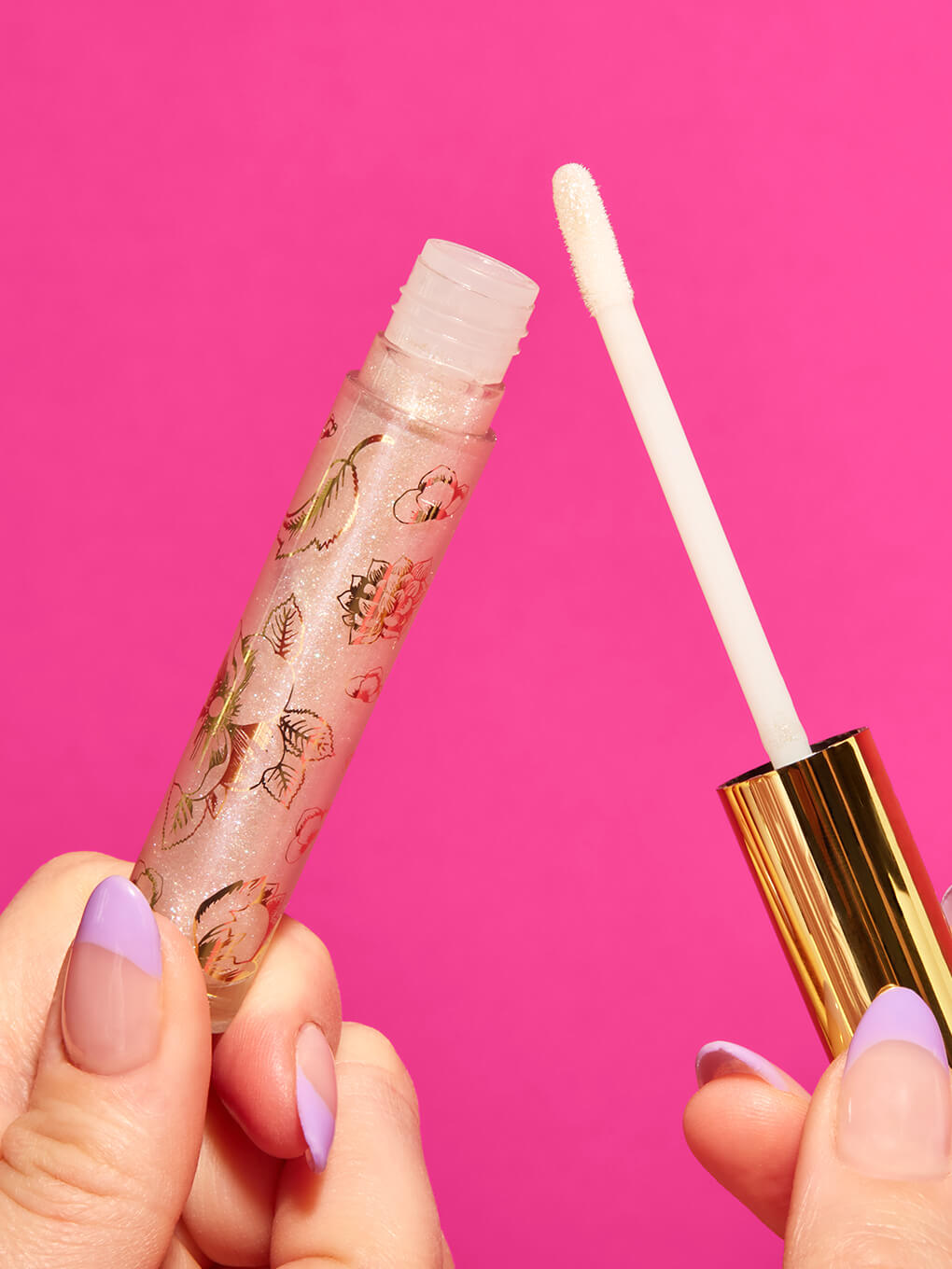 Birthday Cake -- hand holding up glossy boss lip glass cap off on pink background