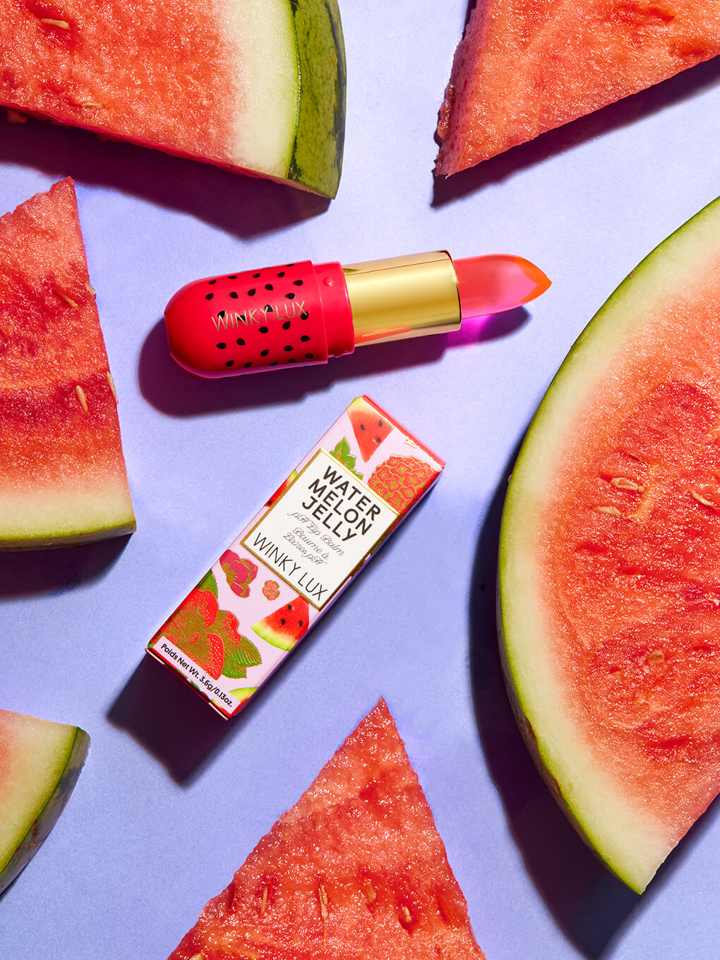 watermelon jelly ph lip balm and box laying down with watermelon on purple background