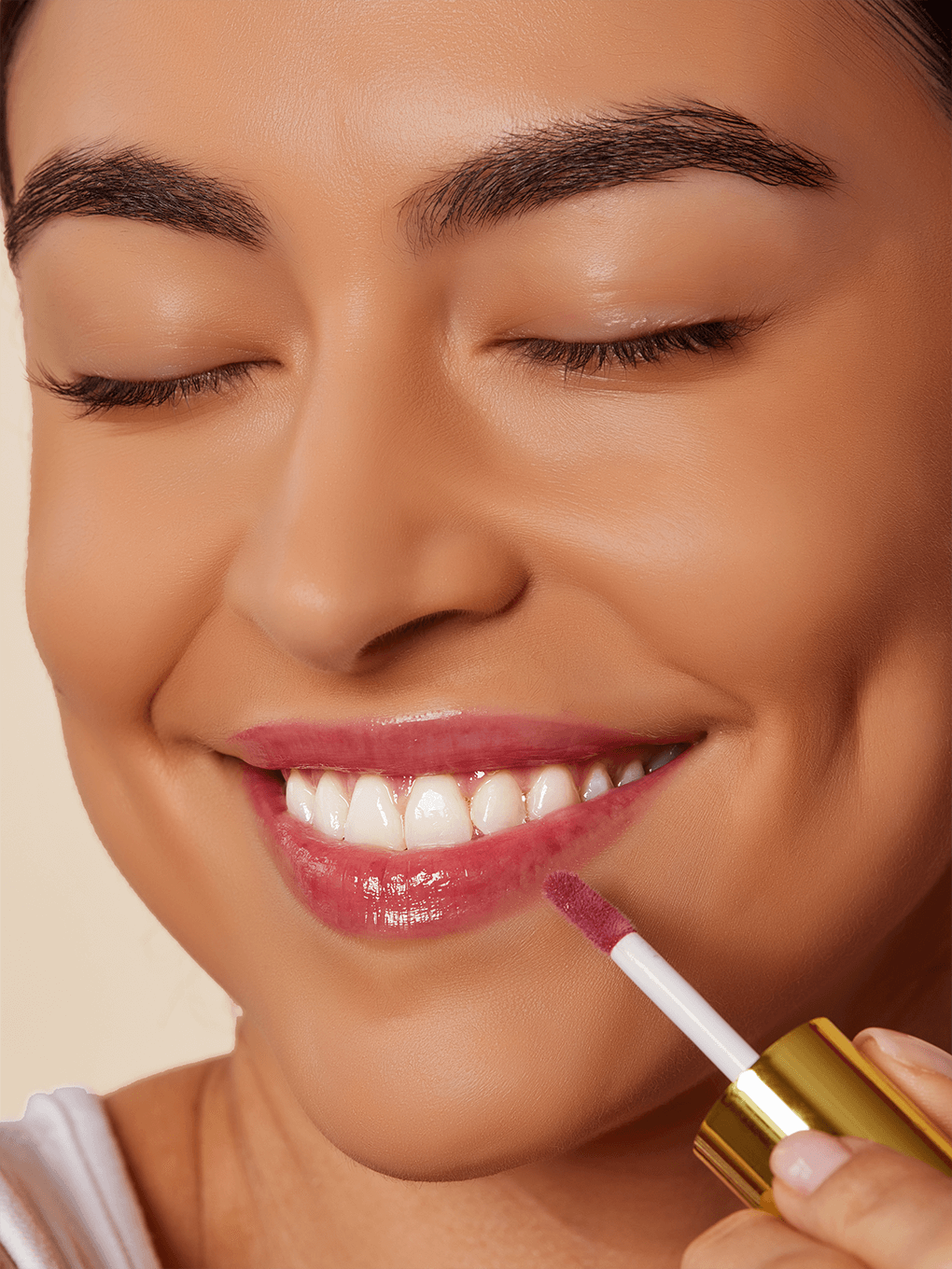 Berry -- close up of model smiling applying berry pink tinted lip oil to lips with eyes closed