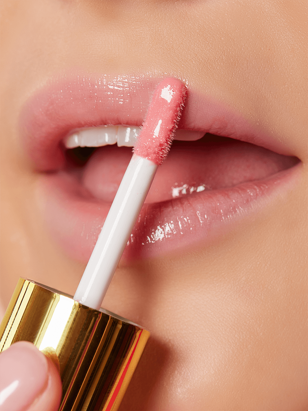 Passion -- close up of model applying sheer pink tinted lip oil to lip with mouth open