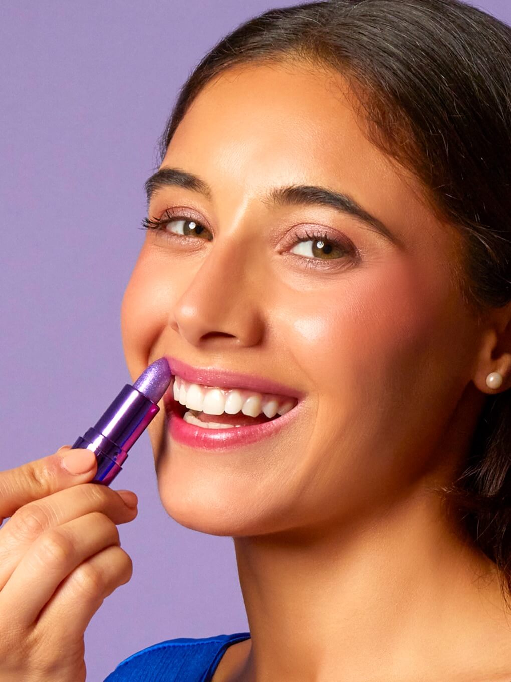 brunette model smiling and applying amethyst ph lip balm to lips