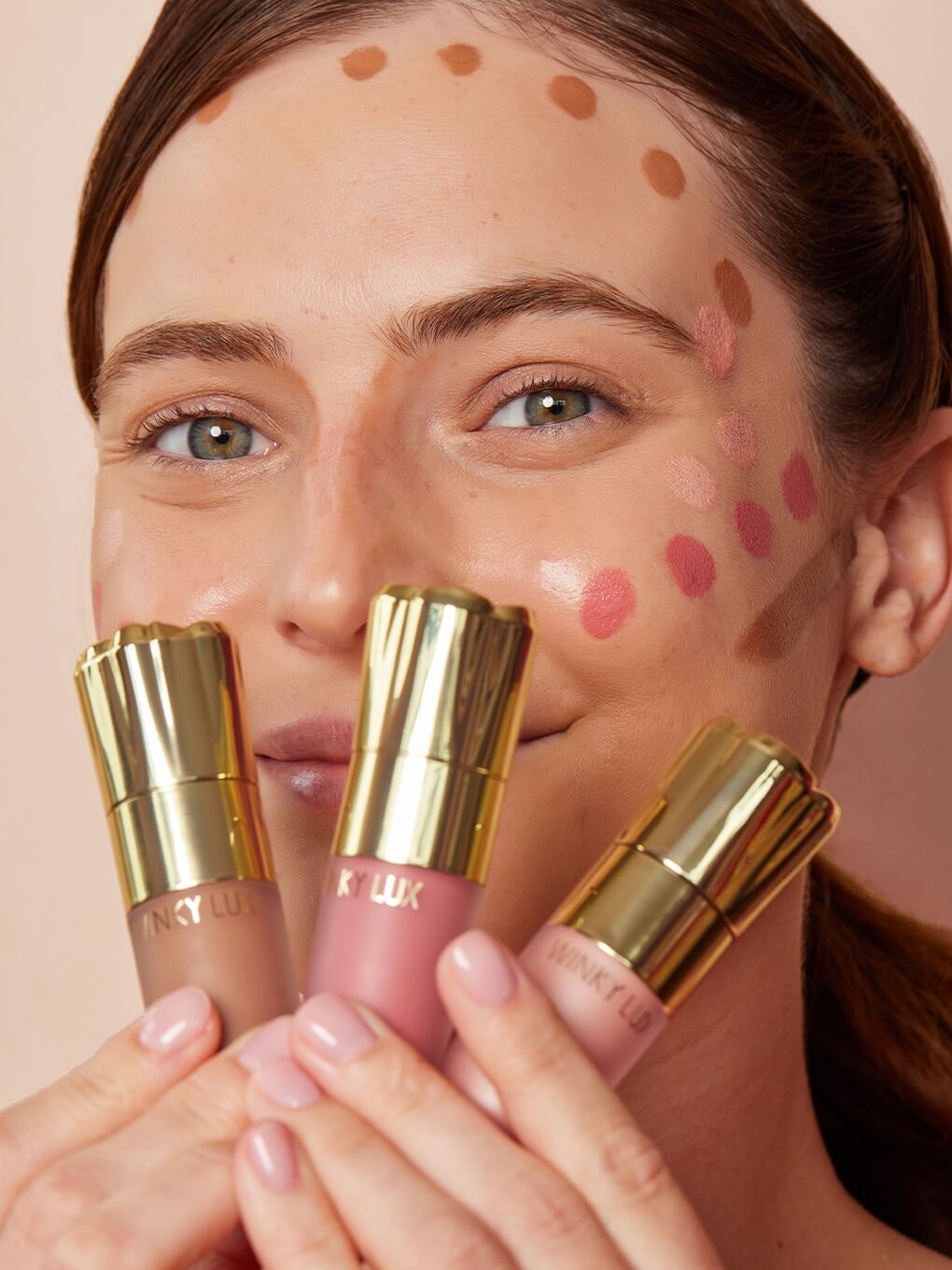 model with cheeky rose liquid bronzer, blush and highlighter dotted on face, holding up product