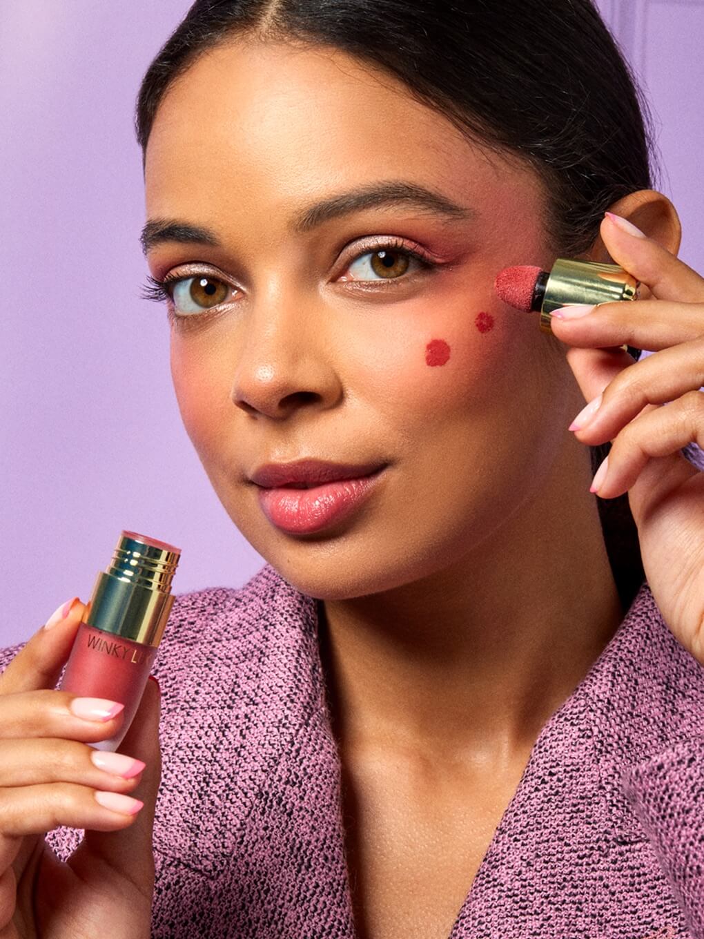 brunette model applying cheeky rose liquid blush to cheekbone