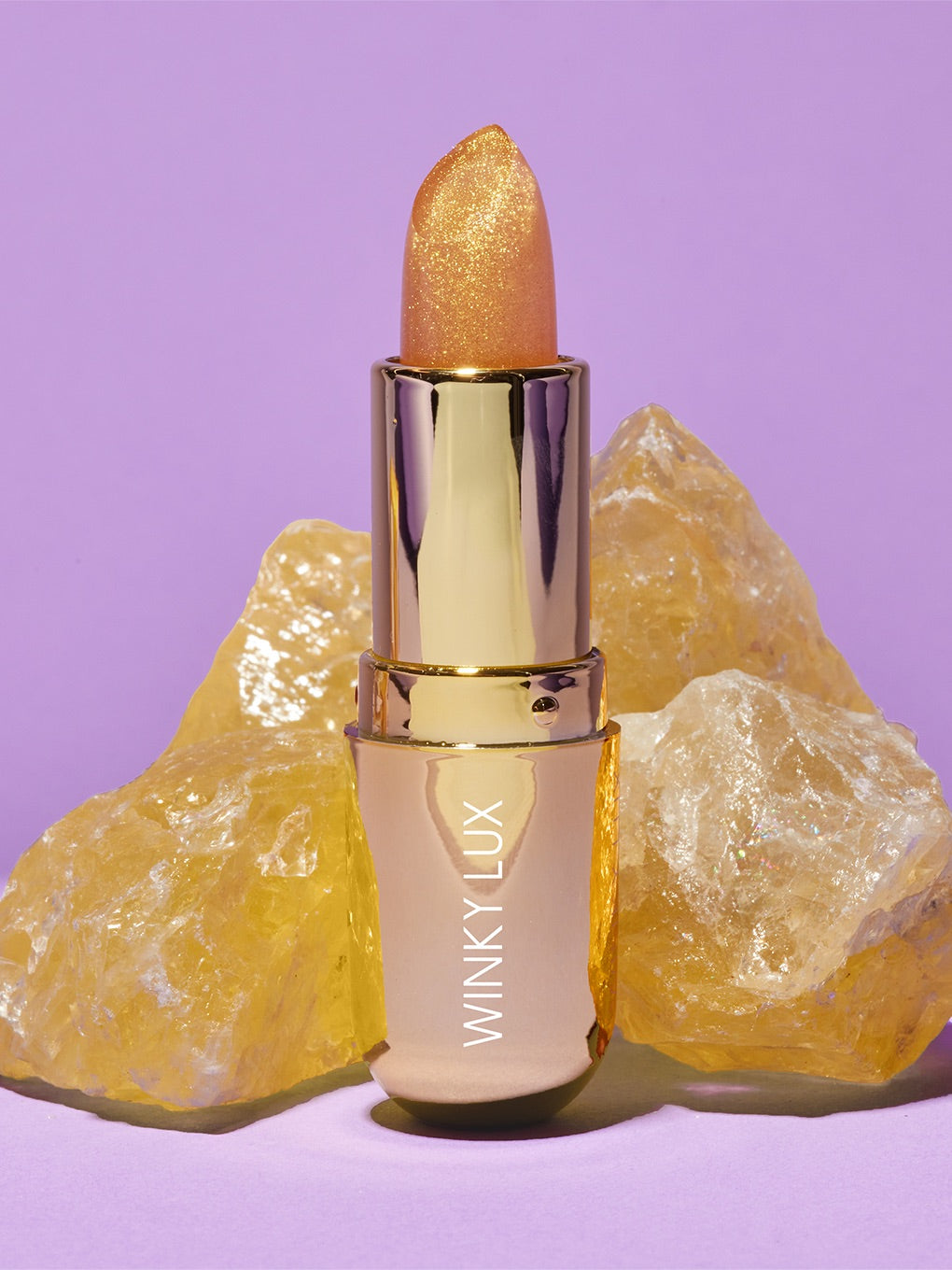 citrine balm standing up next to stone on purple background