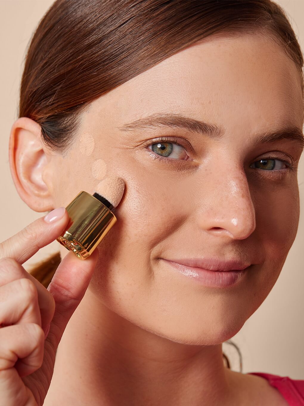 Moonlight -- model applying dots of cheeky rose liquid highlighter to high cheekbone