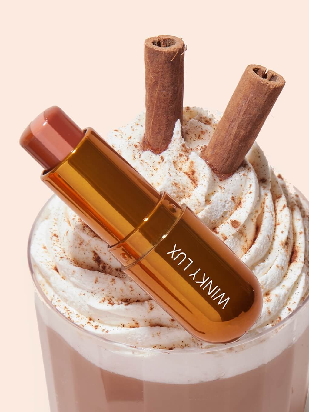 Pumpkin spice latte lip balm lying on top of whipped cream coffee drink