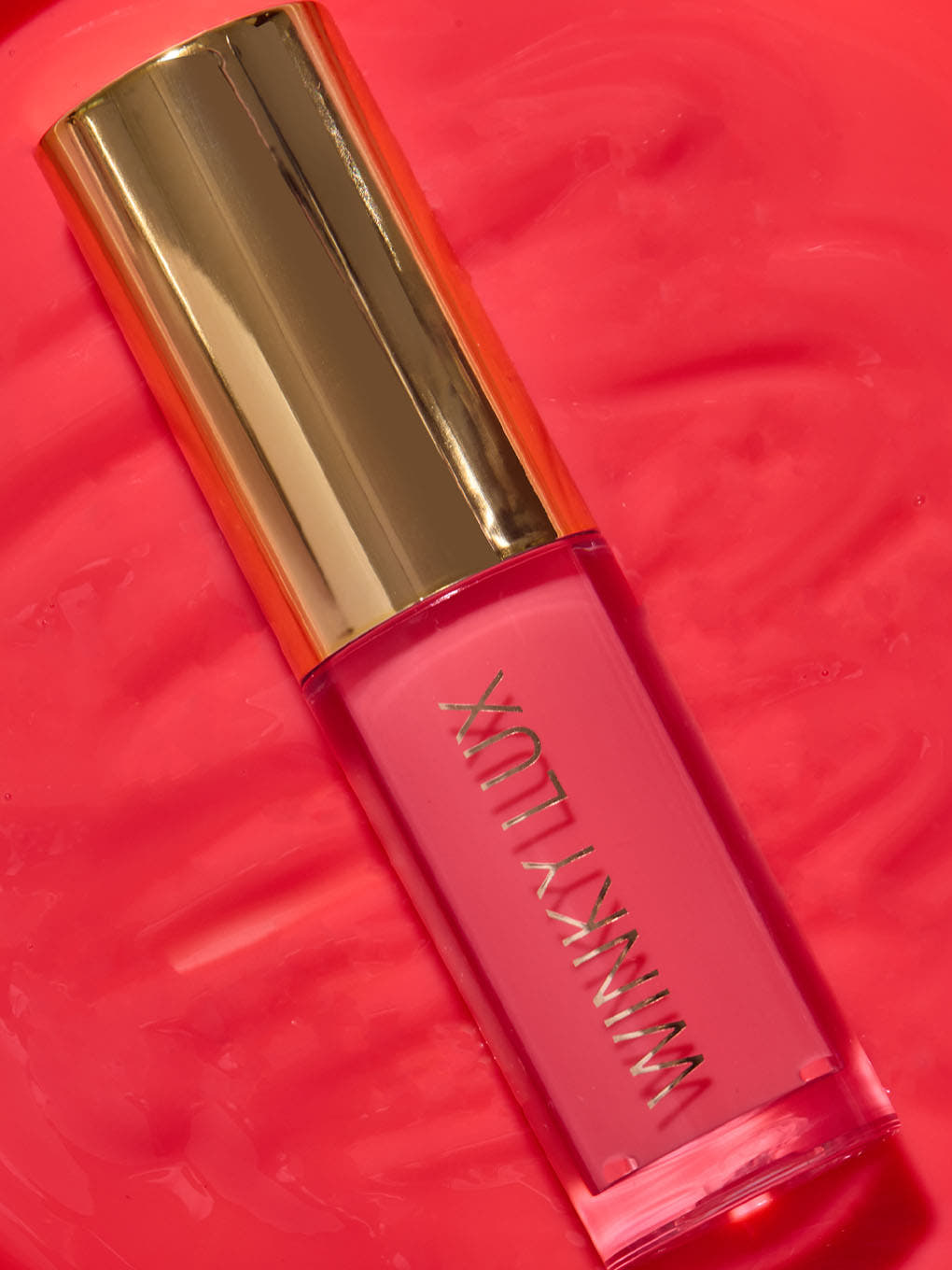juicy -- close up of pink lip oil component lying on top of lip oil goop