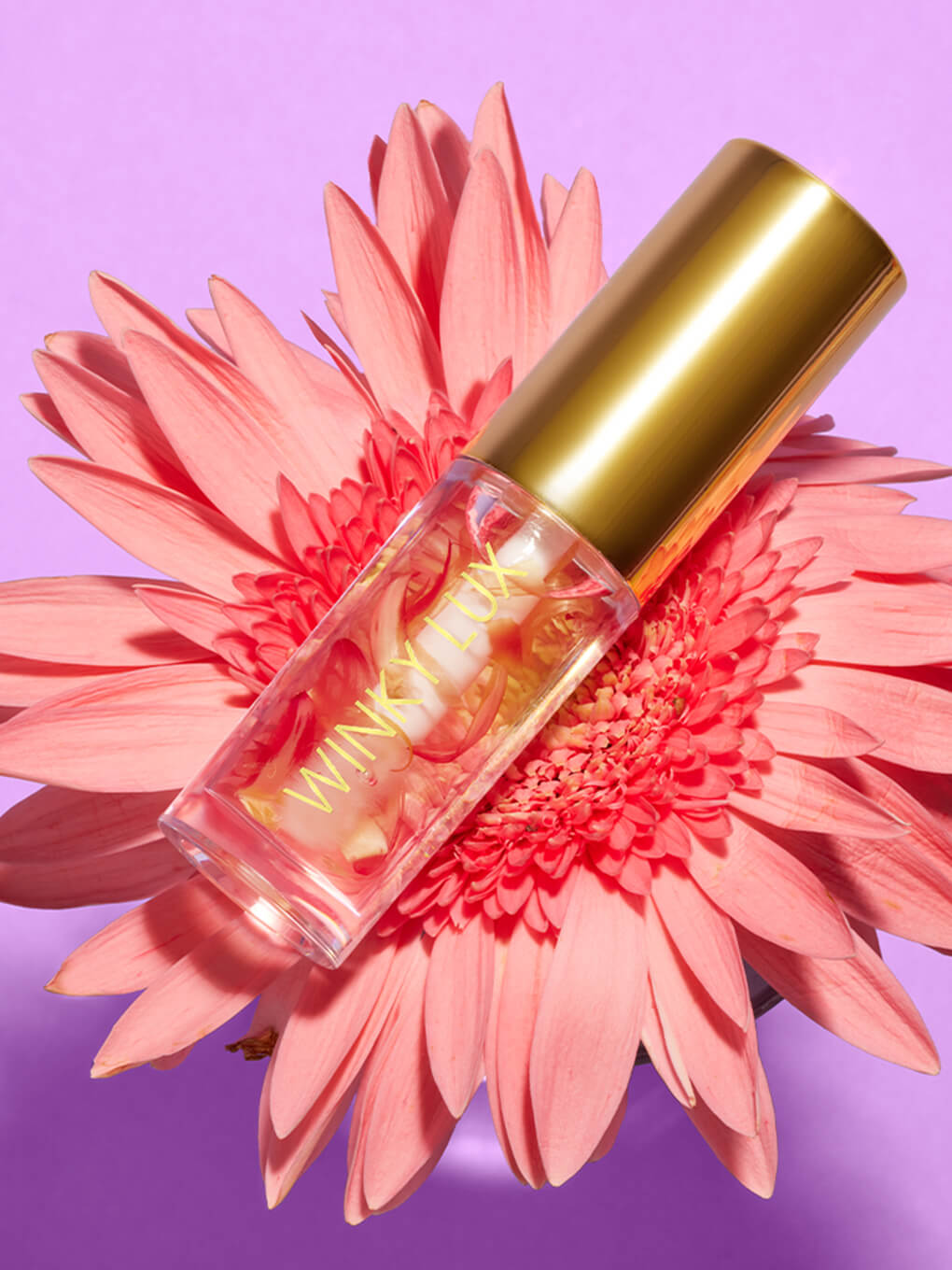 Flower petal lip oil resting in center of pink flower