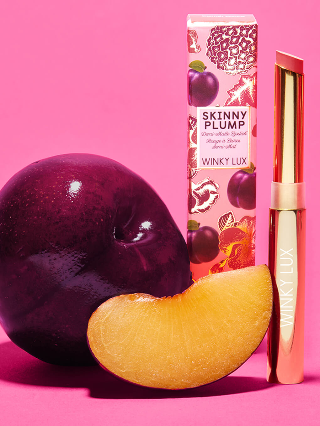 rose hotel -- skinny plump demi matte plumping lipstick standing next to box and plum