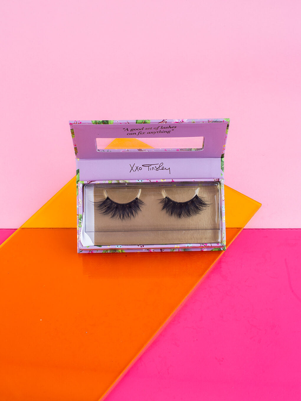 graduate -- fake eyelashes in box with lid open flat lay on pink background