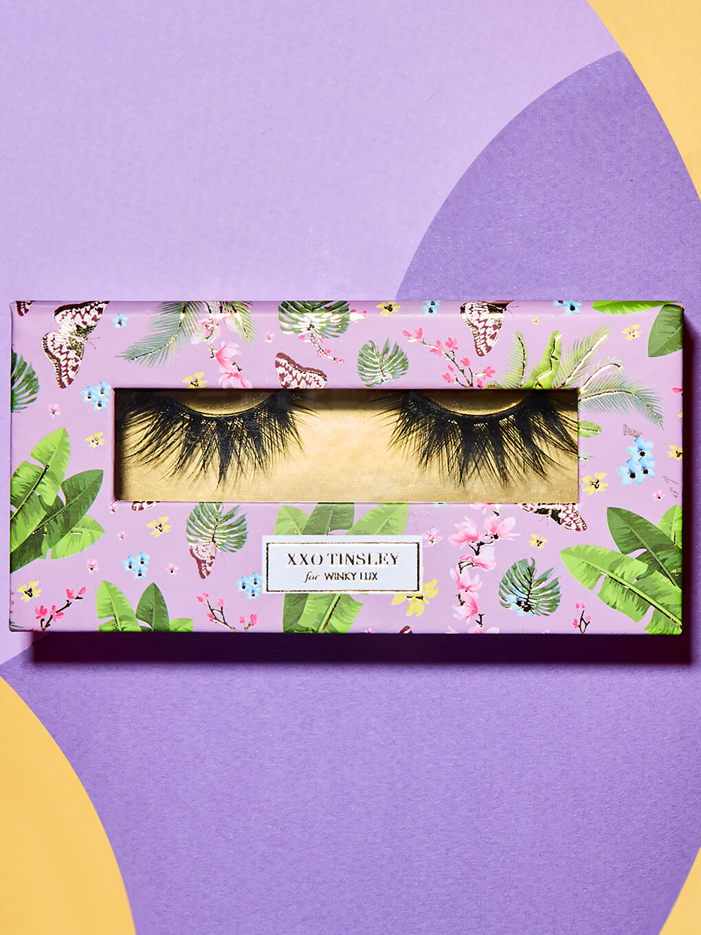 graduate -- fake eyelashes in box flat lay on purple background